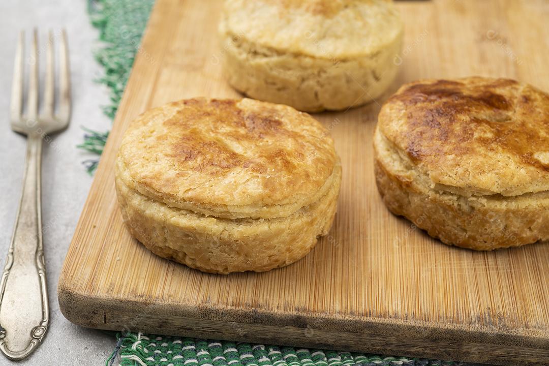 Três tortas caseiras de pelúcia sobre tábua de madeira.