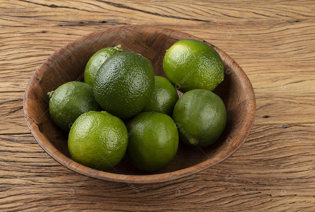 Limões em uma tigela sobre mesa de madeira.