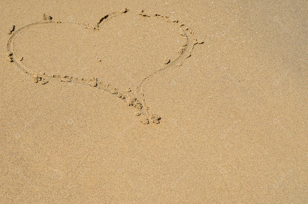 Grande conceito de amor, textura de areia da praia com coração desenhado.