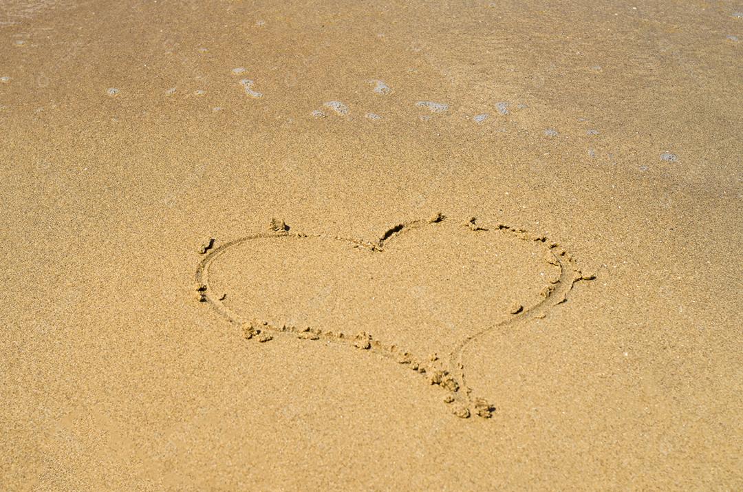 Grande conceito de amor, textura de areia da praia com coração desenhado.