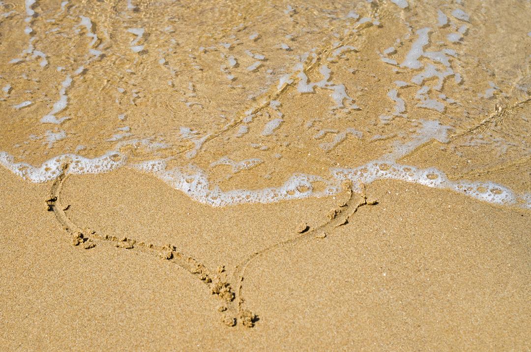 Grande conceito de amor, textura de areia da praia com coração desenhado.