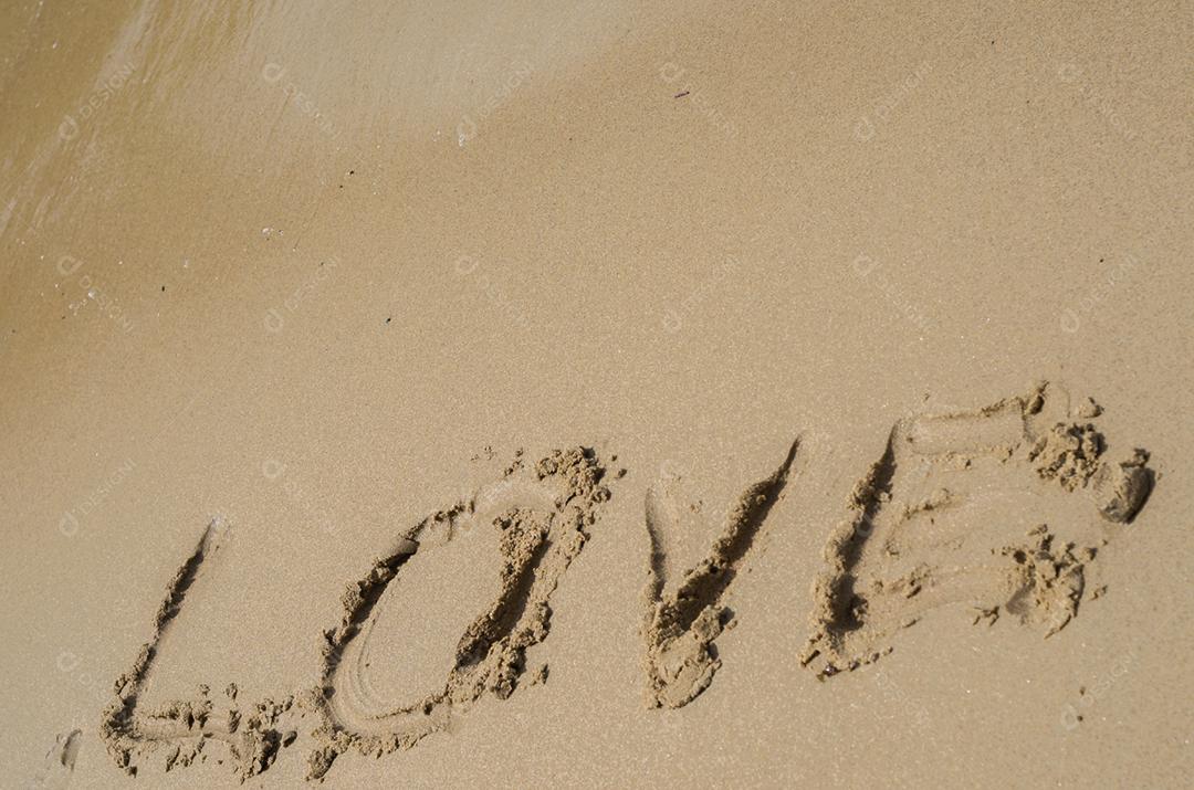 Grande conceito de amor, textura de areia da praia com a palavra amor desenhada.