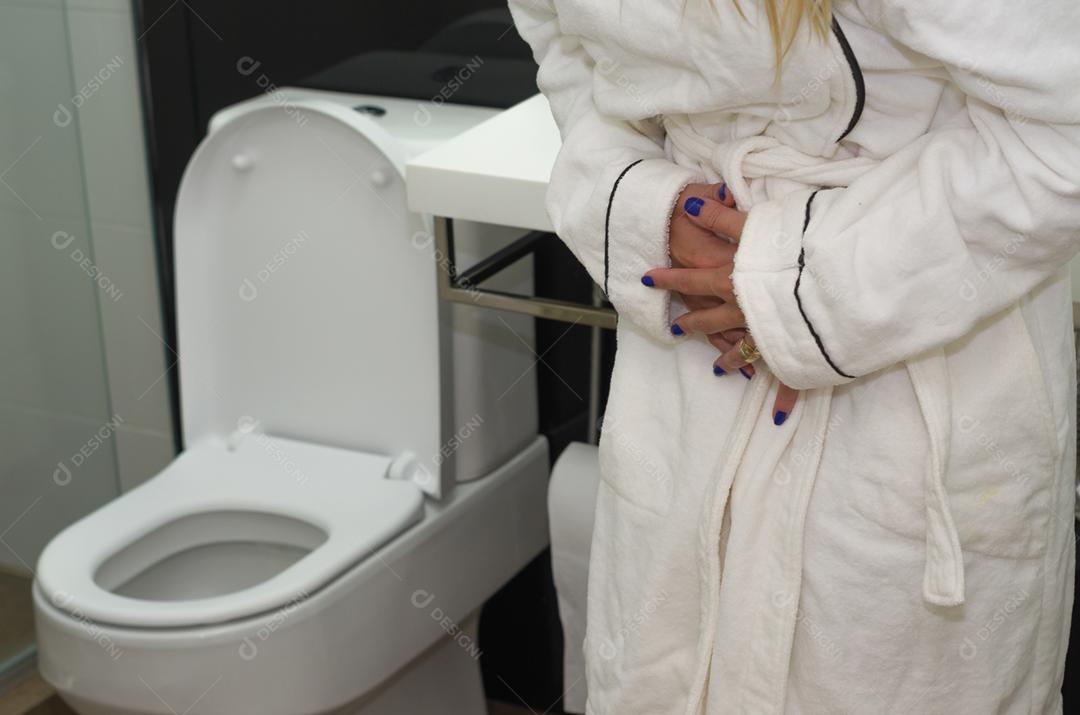 Jovem loira ficando doente, com náuseas no banheiro.