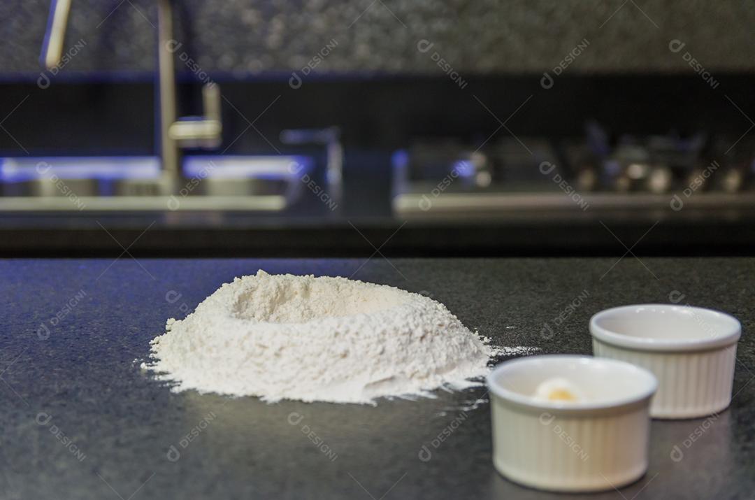 Monte de farinha de trigo em cima da mesa de granito preto, preparação de massa de pizza.