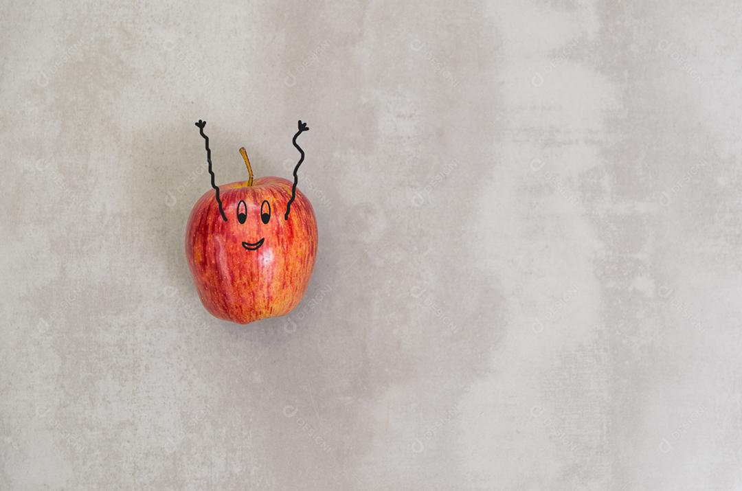 Grande conceito de alimentação saudável, maçã com cara feliz e braços para cima em fundo cinza.