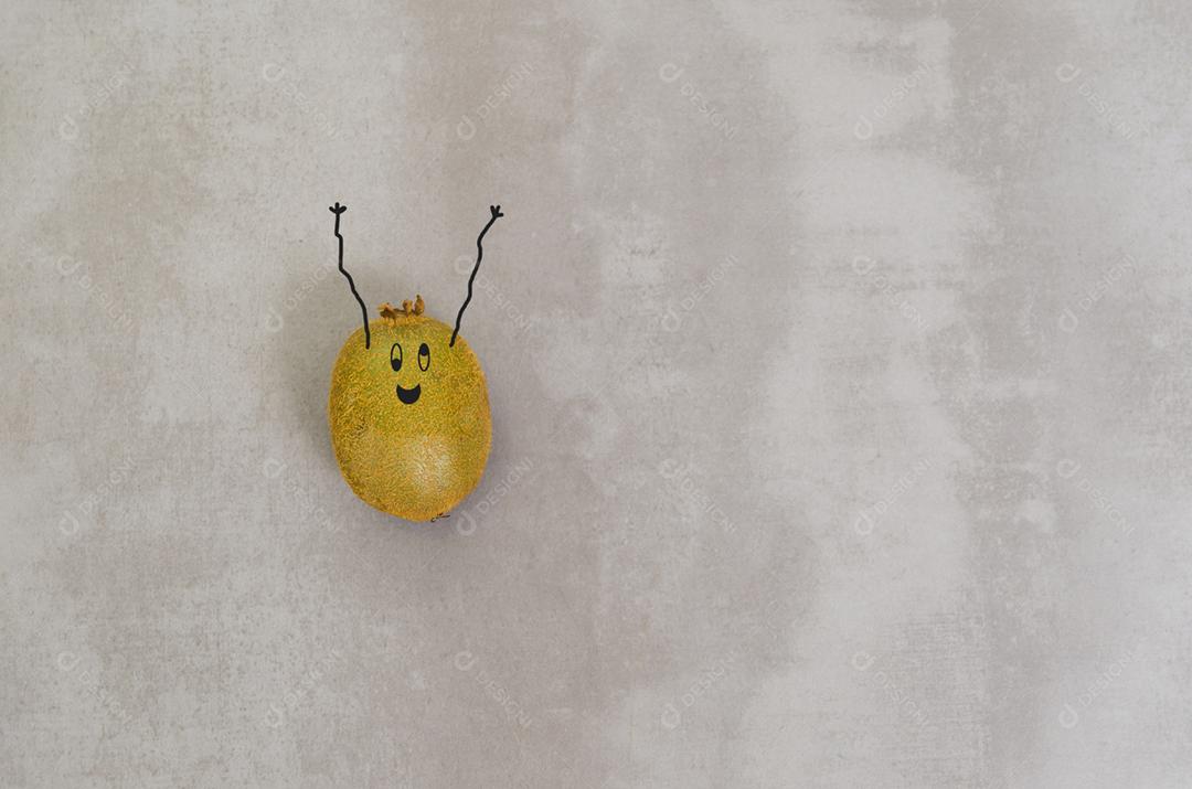 Grande conceito de alimentação saudável, kiwi com cara de feliz e braços para cima em fundo cinza.