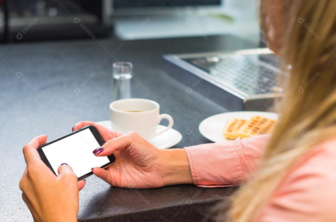 Jovem mulher usando smartphone bebendo café, café da manhã.