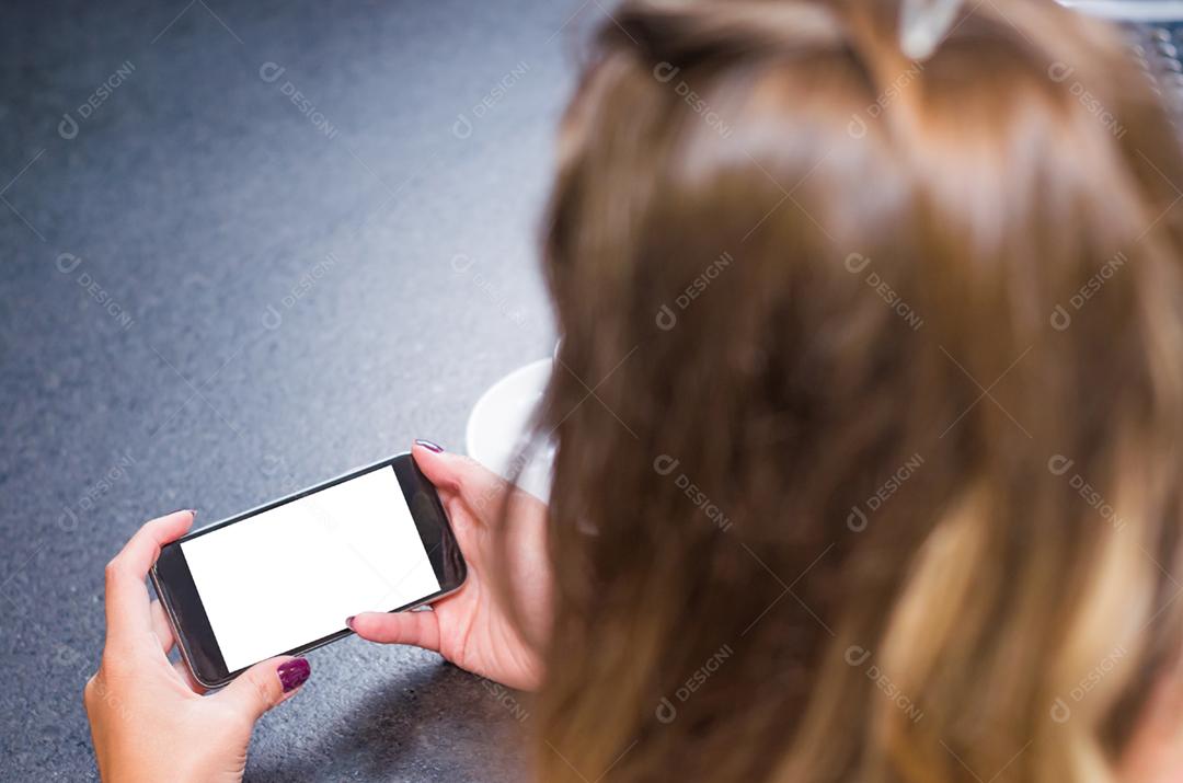 Jovem mulher usando smartphone bebendo café, café da manhã.