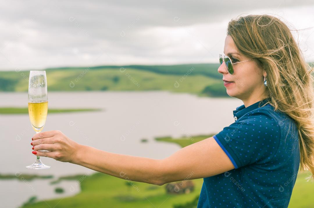 Jovem mulher segurando o copo de espumante (champanhe)