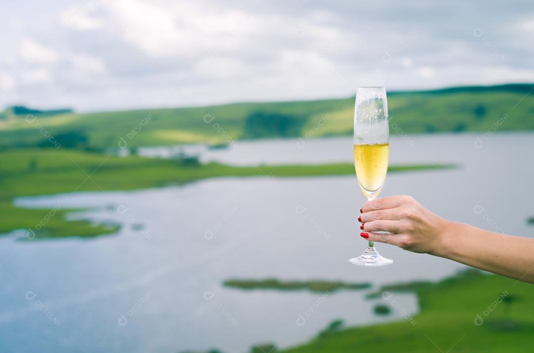 Jovem mulher segurando o copo de espumante (champanhe)