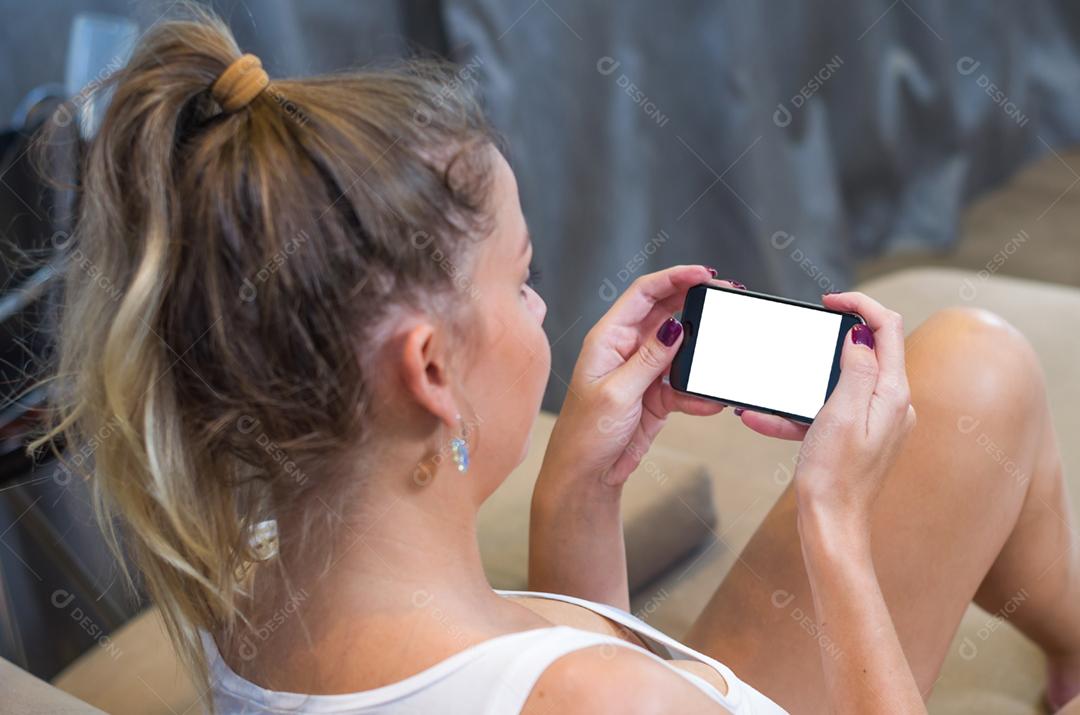 Jovem mulher usando smartphone bebendo café da manhã.