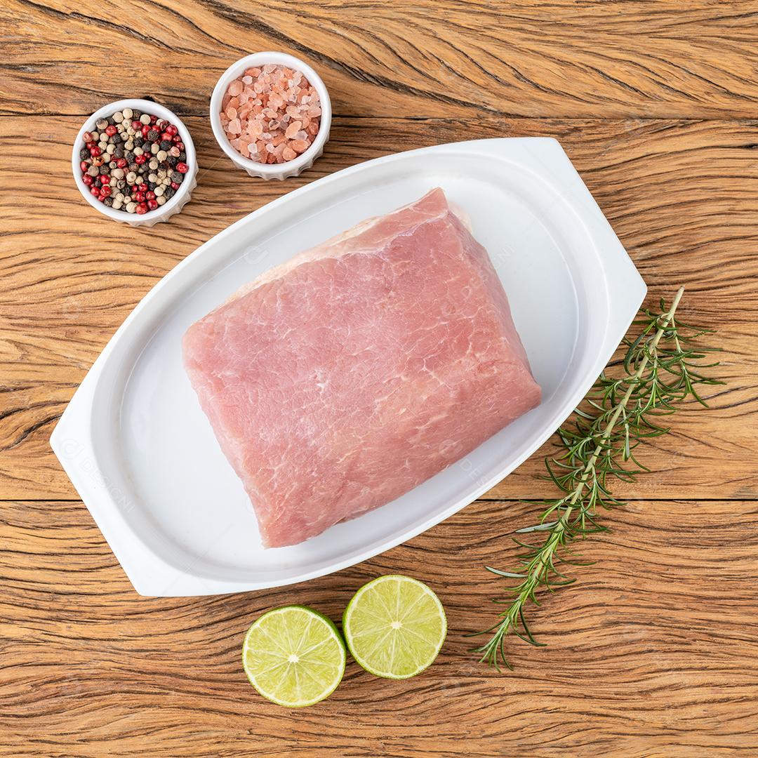 Carne de lombo de porco crua sobre tábua de madeira com temperos.