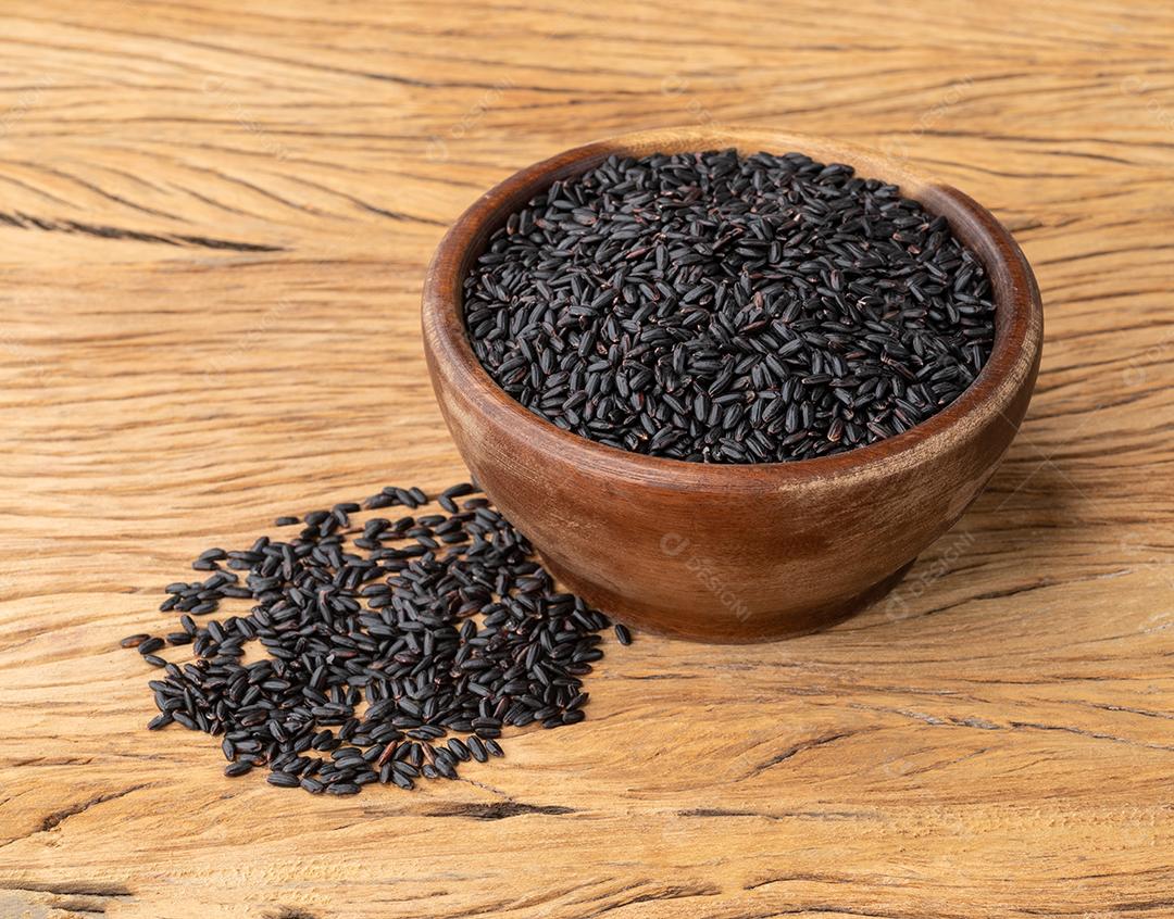 Arroz preto cru em uma tigela sobre mesa de madeira