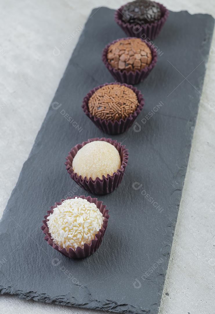 Brigadeiros típicos brasileiros, vários sabores sobre prancha de pedra, baixa profundidade de campo.