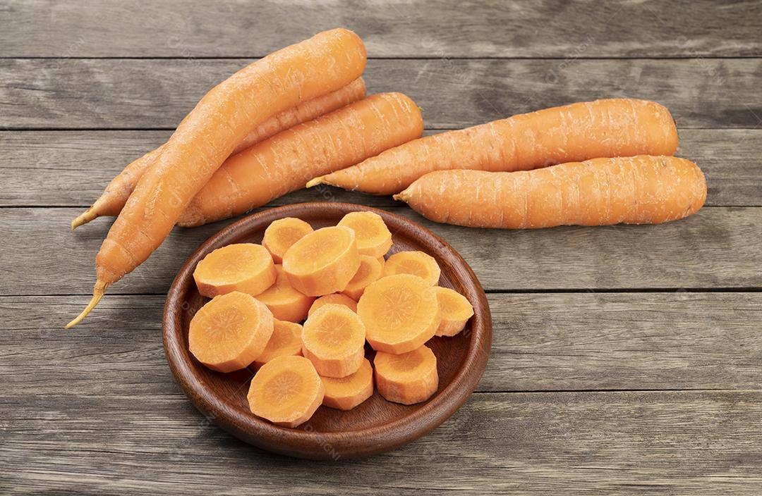 Cenouras e fatias em um prato sobre mesa de madeira.