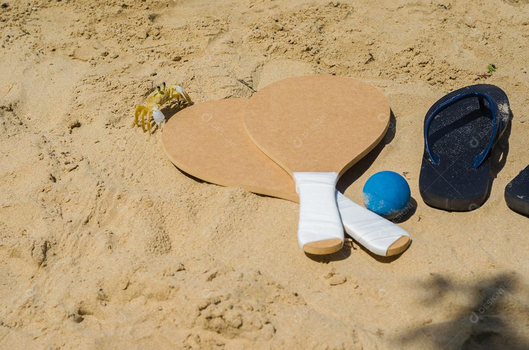 Caranguejo olhando raquetes de tênis de praia de areia, bebida caipirinha