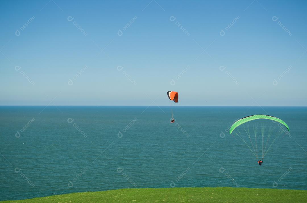 Estudantes praticando parapente na colina.