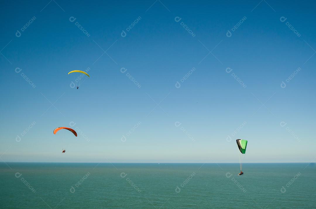 Estudantes praticando parapente na colina.