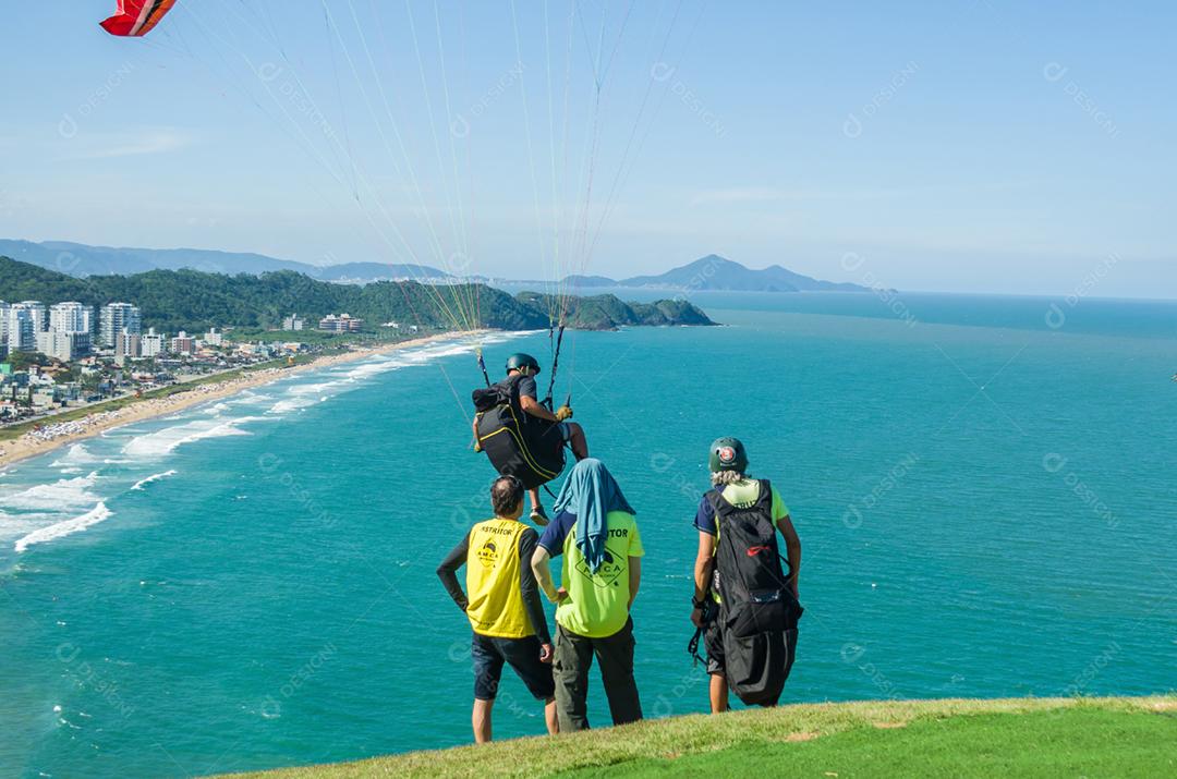 Estudantes praticando parapente na colina.