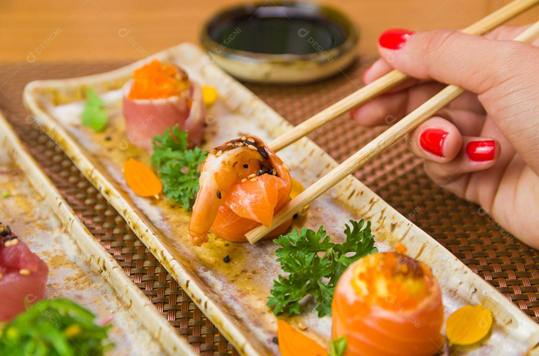 Mulher comendo sushi delicioso, closeup em pauzinhos.