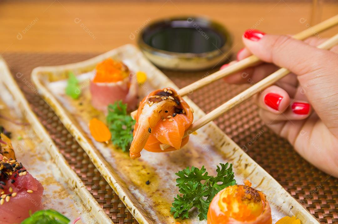 Mulher comendo sushi delicioso, closeup em pauzinhos.