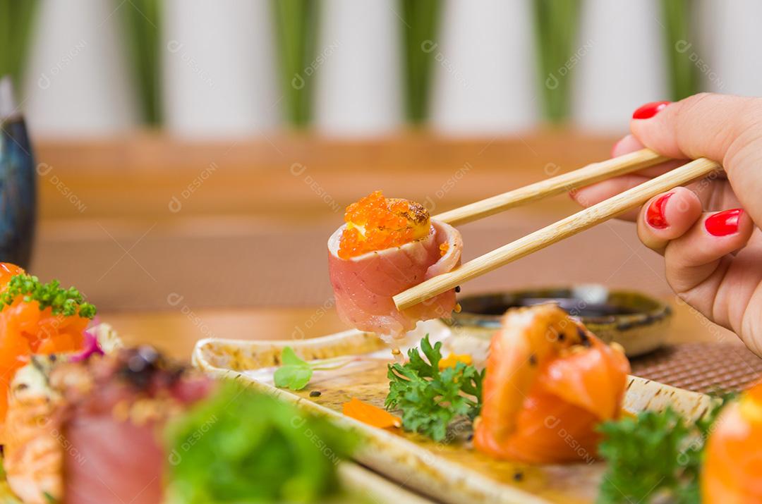 Mulher comendo sushi delicioso, closeup em pauzinhos.