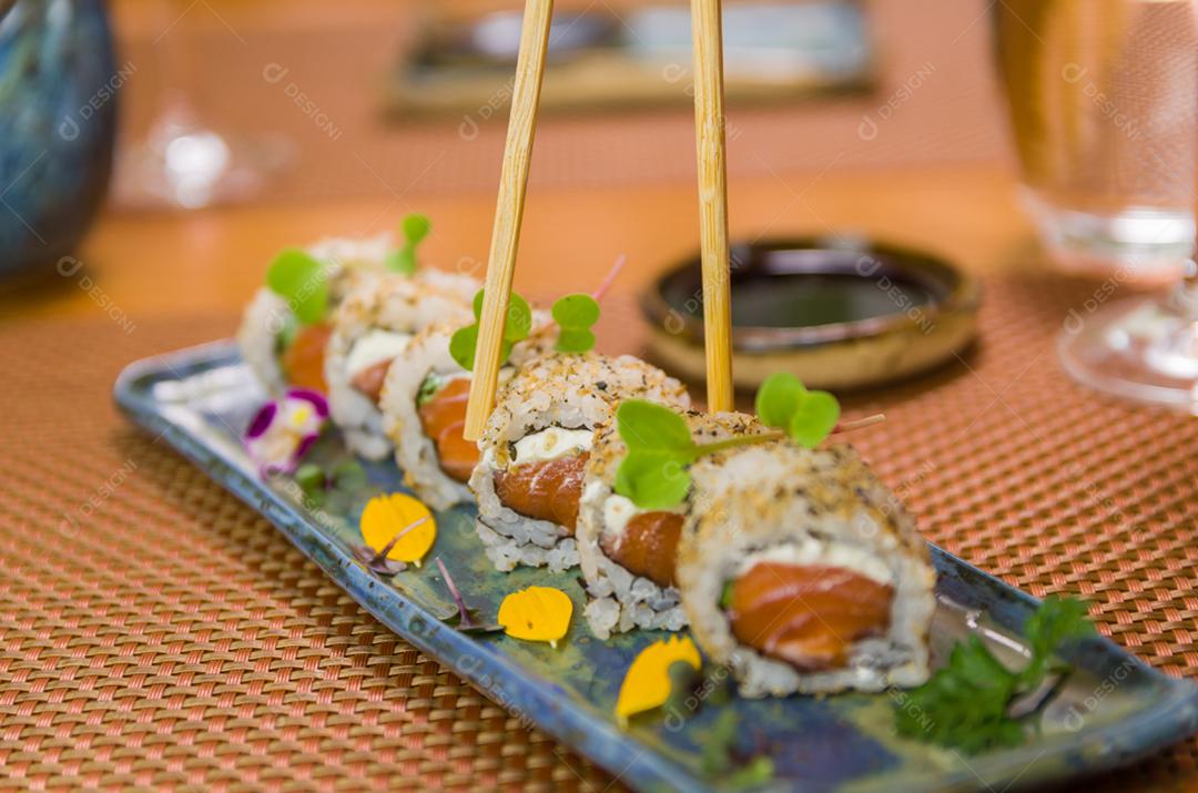 Mulher comendo delicioso sushi gunkan, closeup em pauzinhos