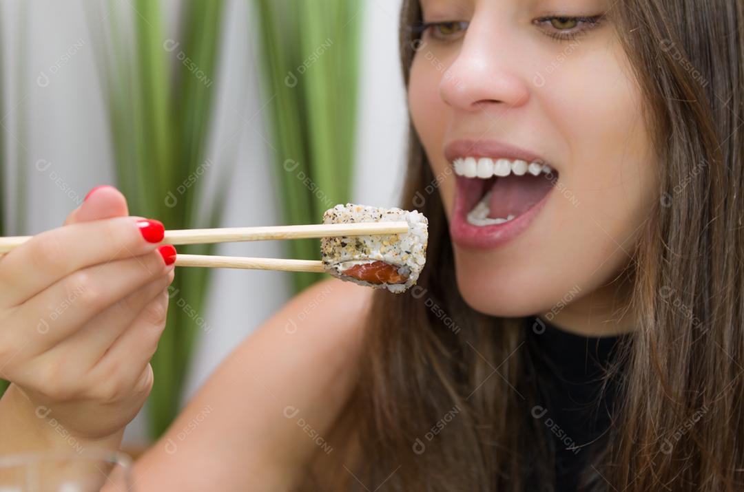 Mulher comendo sushi delicioso, closeup em pauzinhos