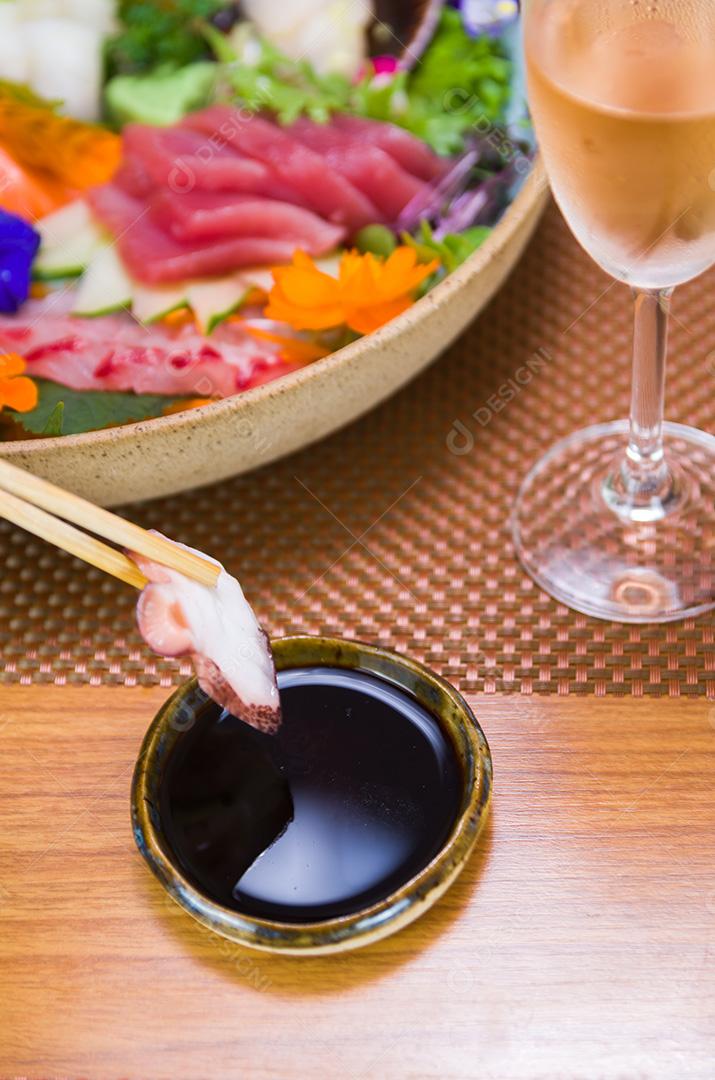 Mulher comendo delicioso sashimi, closeup em pauzinhos.