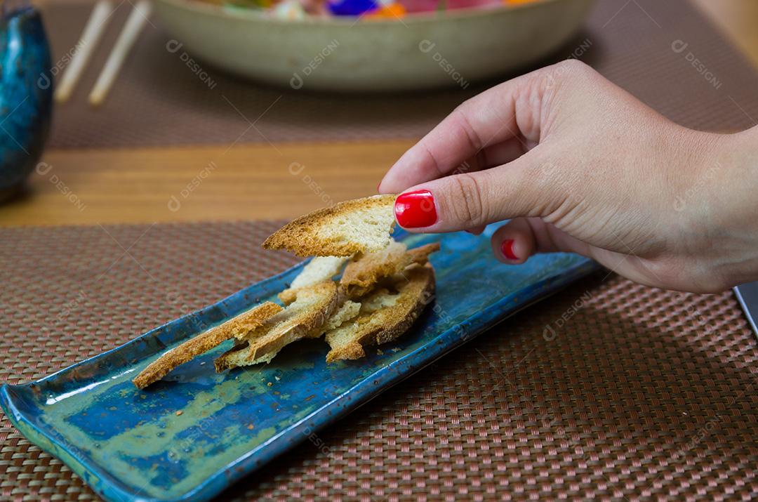 Mulher tomando fatias de pão torrado em lindo prato decorado