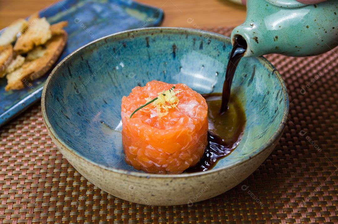 Homem transformando molho de soja em delícias de tártaro de salmão em uma bea