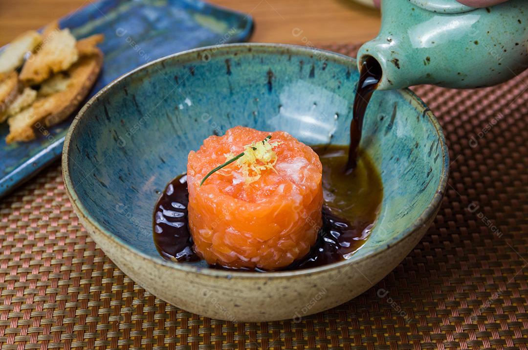 Homem transformando molho de soja em delícias de tártaro de salmão em uma bea
