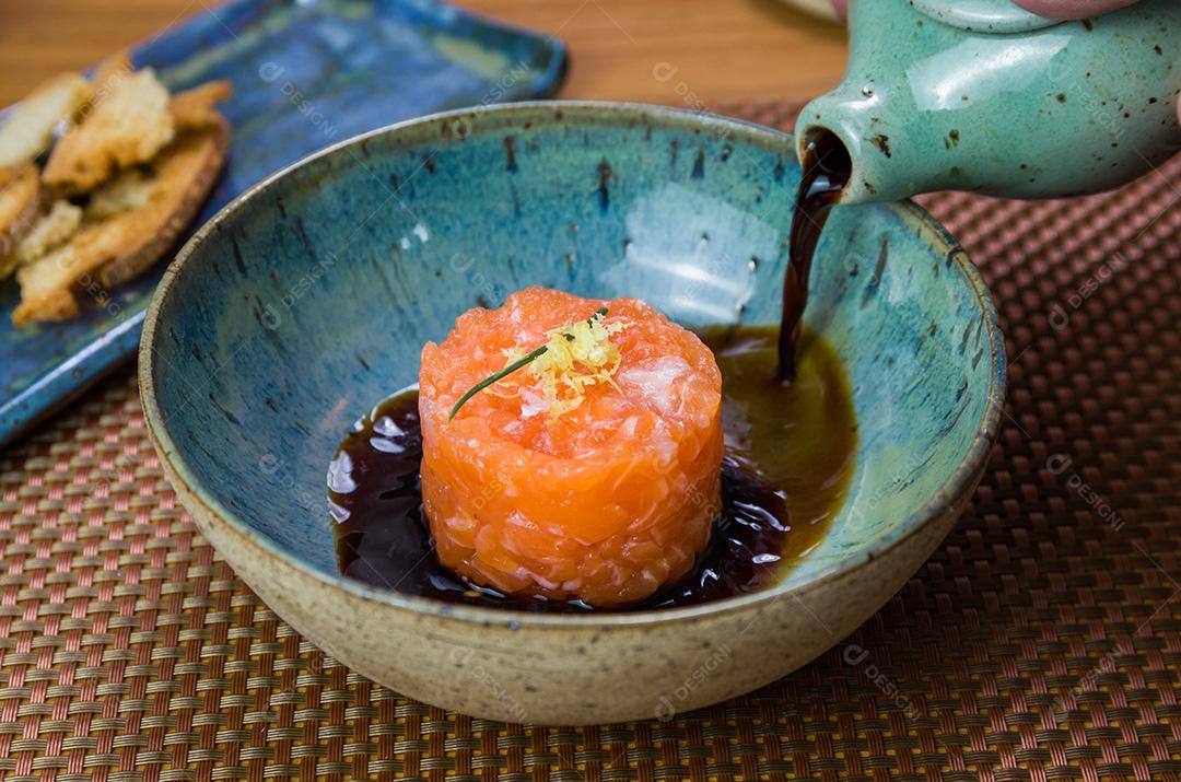 Homem transformando molho de soja em delícias de tártaro de salmão em uma bea