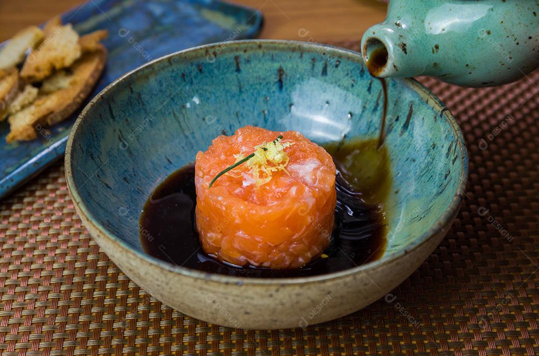 Homem transformando molho de soja em delícias de tártaro de salmão em uma bea