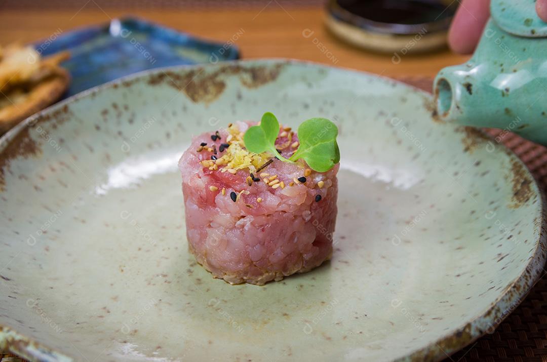 Homem derramando molho de soja em delícias de tártaro de atum em um belo de