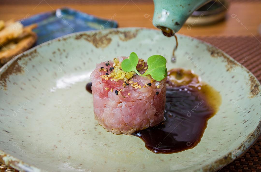 Homem derramando molho de soja em delícias de tártaro de atum em um belo de