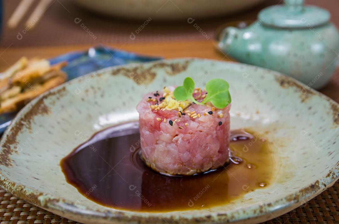 Homem derramando molho de soja em delícias de tártaro de atum em um belo de