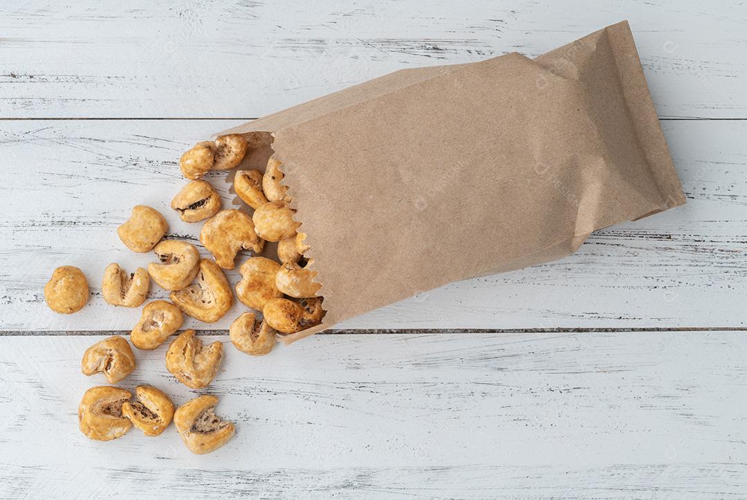 Canjica, canjica ou pipoca de milho branco, pipoca doce em um saco sobre mesa de madeira.