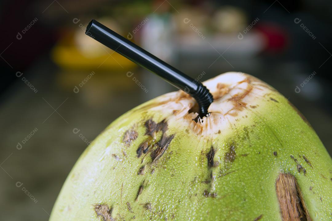 Detalhe de coco verde com palha preta sobre um fundo de pedra