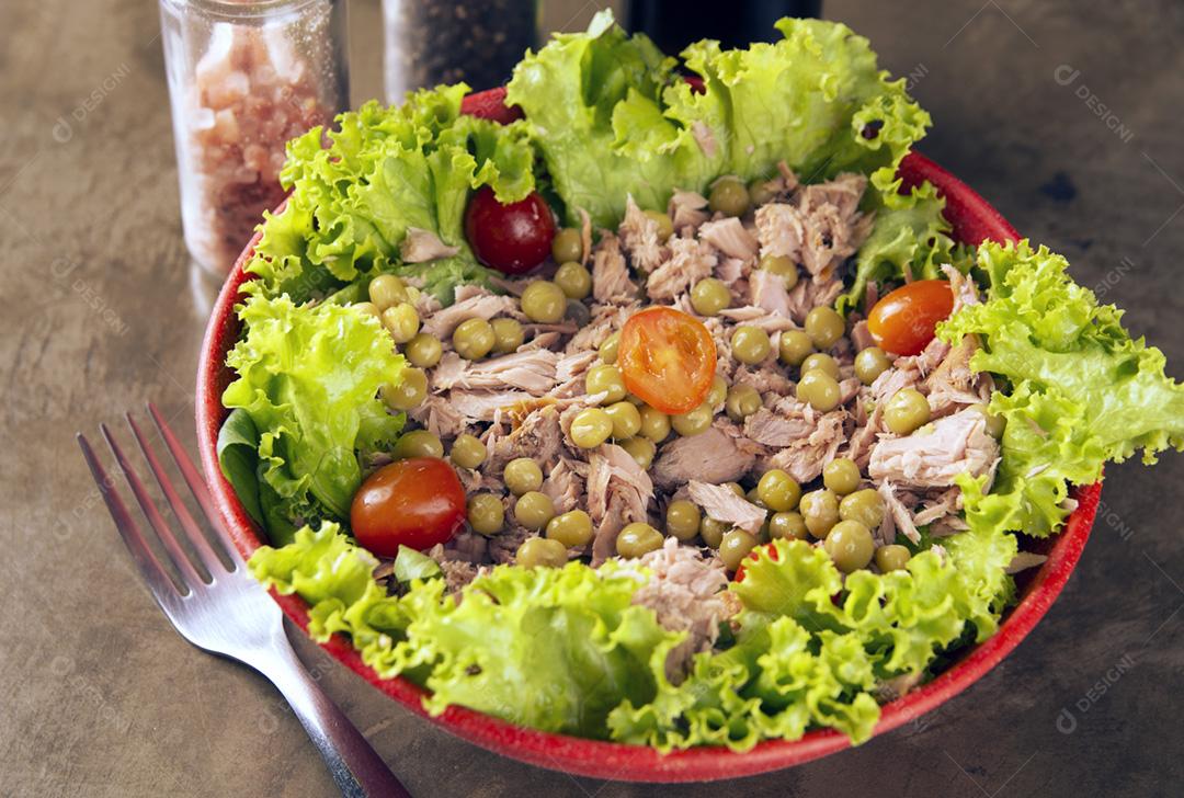 Saladas em tigelas coloridas, sal, pimenta e garrafa de azeite por cima