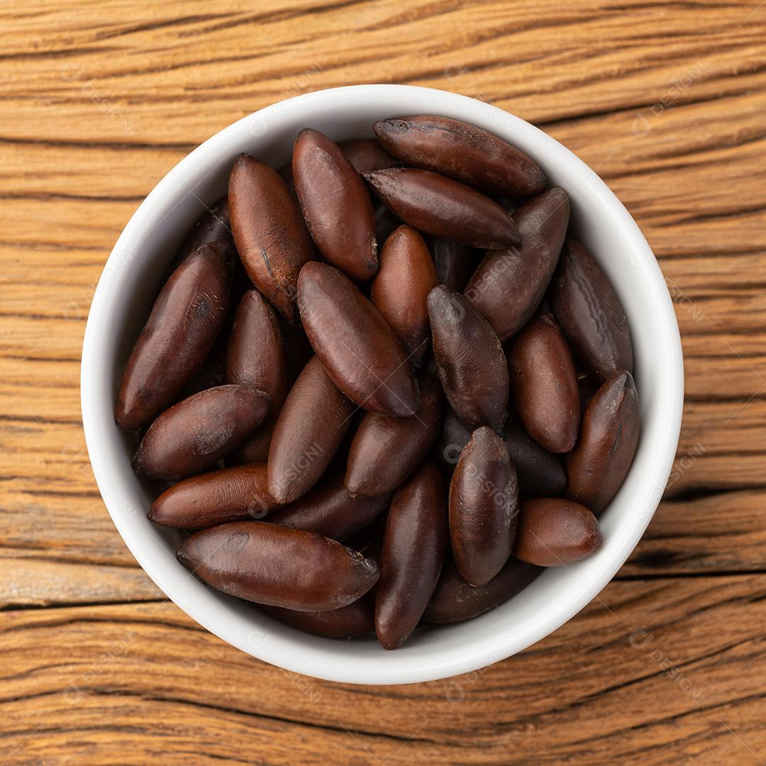 Tigela de castanhas de baru brasileira sobre mesa de madeira.