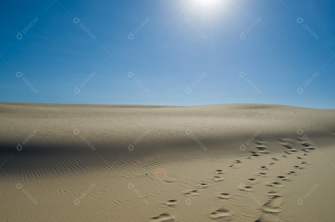 Dunas de areia com céu azul e sol