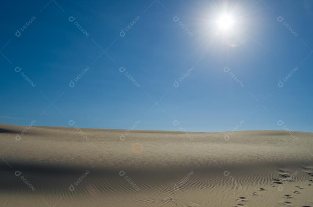 Dunas de areia com céu azul e sol