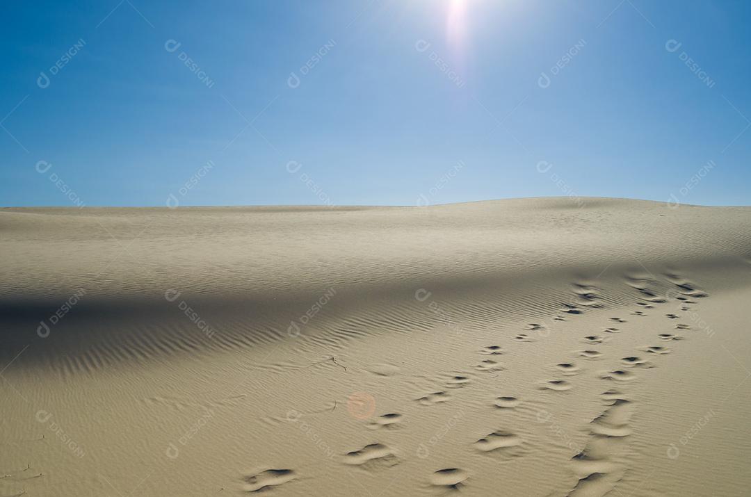 Dunas de areia com céu azul e sol