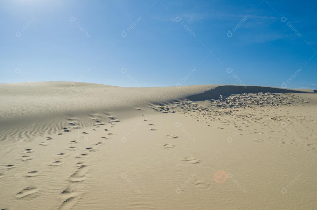 Dunas de areia com céu azul e sol