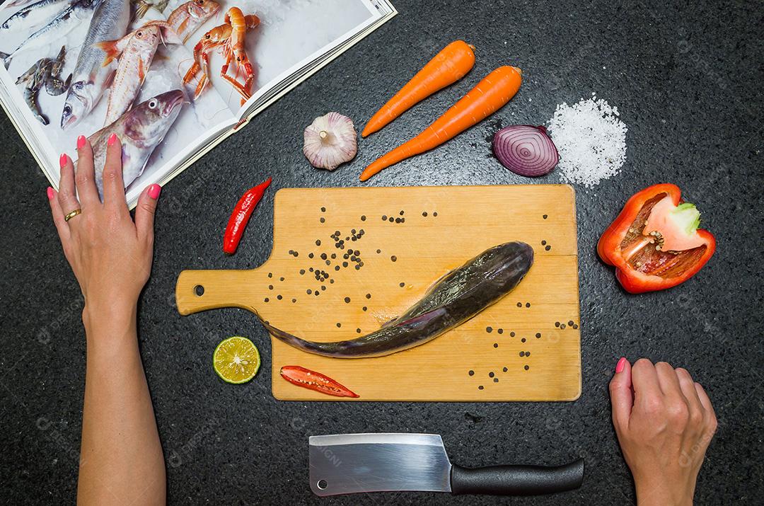 Preparando um peixe-gato gastronômico de prato de peixe, mãos de mulher caucasiana