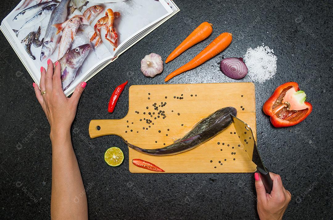 Preparando um peixe-gato gastronômico de prato de peixe, mãos de mulher caucasiana