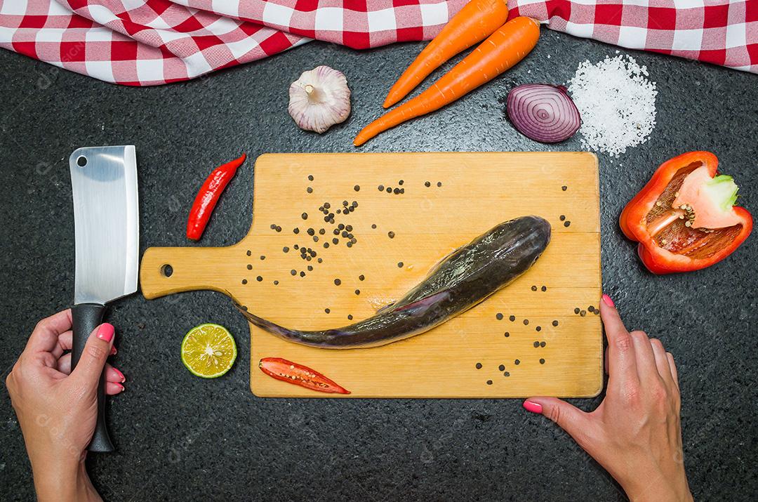 Preparando um peixe-gato gastronômico de prato de peixe, mãos de mulher caucasiana