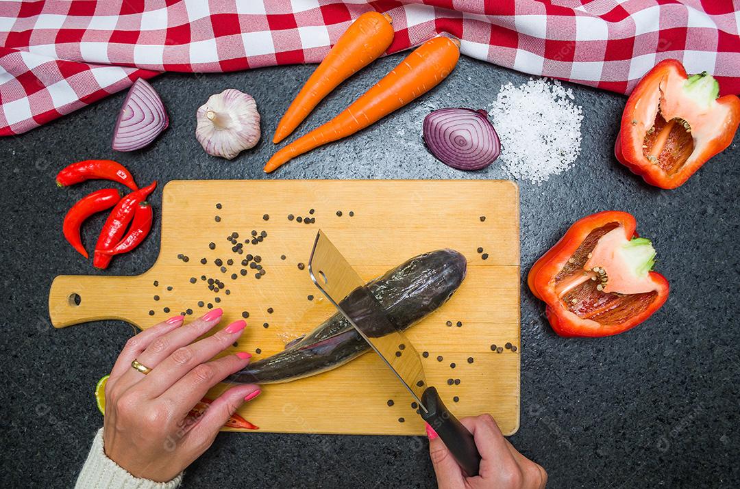 Preparando um peixe-gato gastronômico de prato de peixe, mãos de mulher caucasiana
