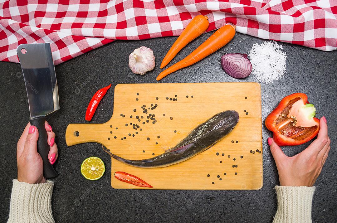 Preparando um peixe-gato gastronômico de prato de peixe, mãos de mulher caucasiana